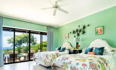 two beds in a room with green walls at Casa Serena Luxury Retreat in Reserva Conchal in Brasilito