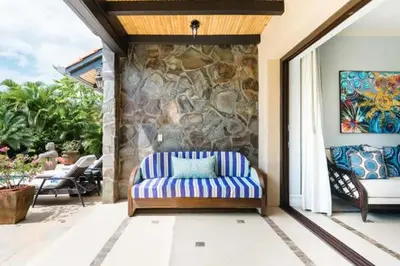 a porch with a couch and a stone wall at Casa Serena Luxury Retreat in Reserva Conchal in Brasilito