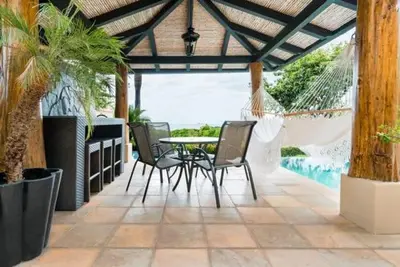 a patio with a table and chairs and a pool at Casa Serena Luxury Retreat in Reserva Conchal in Brasilito