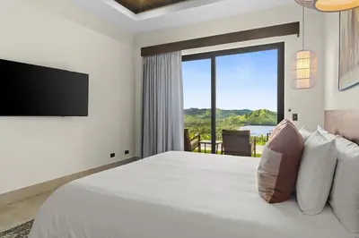 a bedroom with a large bed with a large window at Luxury Ocean View Villa in Playa Hermosa