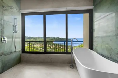 a bathroom with a bath tub and a large window at Luxury Ocean View Villa in Playa Hermosa