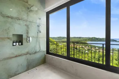 a bathroom with a shower with a large window at Luxury Ocean View Villa in Playa Hermosa