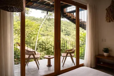 a bedroom with a bed and two chairs on a balcony at Santa Hermosa Honey moon Villa in Santiago