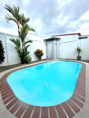 a large blue swimming pool in front of a building at Family home in Bejuco with pool and beach access in Bejuco