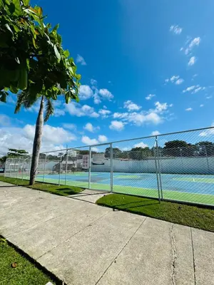 a tennis court behind a fence with a palm tree at Family home in Bejuco with pool and beach access in Bejuco