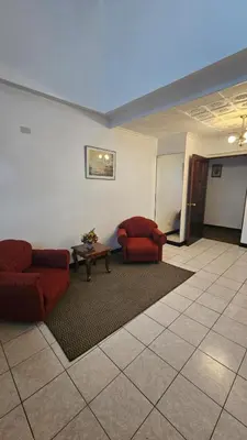 a living room with two red chairs and a table at Hotel Valladolid in Heredia