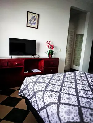 a bedroom with a bed and a flat screen tv at Hotel Valladolid in Heredia