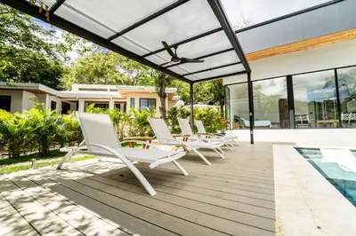 a group of white lounge chairs on a wooden deck at Casa McCash in Tamarindo