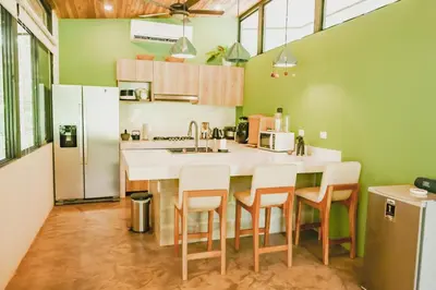 a kitchen with green walls and a kitchen island with chairs at Avellanas Private Villa in Santa Cruz
