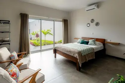 a bedroom with a bed and a large window at Calathea Arenal Villa in Agua Azul