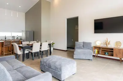a living room with a table and chairs and a kitchen at Calathea Arenal Villa in Agua Azul