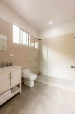 a bathroom with a toilet and a glass shower at Calathea Arenal Villa in Agua Azul