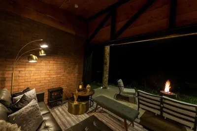 a patio with a couch and a fire pit at night at Cabaña Moderna de Montaña en Zarcero con Vistas y Bosque Neblinoso in Zarcero