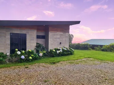 a building with flowers in front of a yard at Cabaña Moderna de Montaña en Zarcero con Vistas y Bosque Neblinoso in Zarcero
