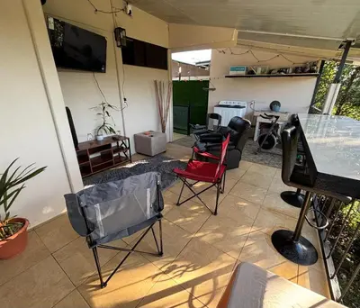 a living room with chairs and a table and a tv at Tu casa de habitación en Sarapiquí, Costa Rica in Pedregal