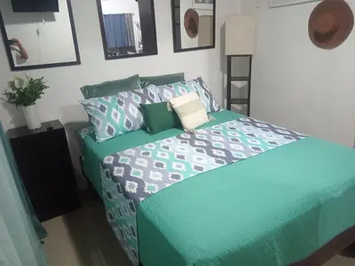 a bedroom with a bed with a green comforter and pillows at Fruta de mango #2 in Lagunillas