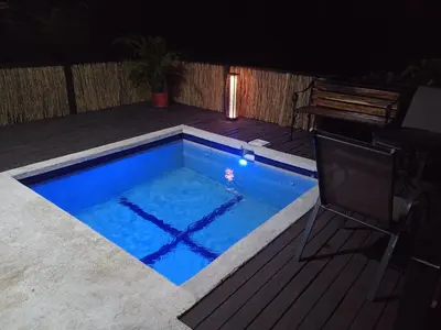 a swimming pool at night with a bench next to it at Fruta de mango #2 in Lagunillas