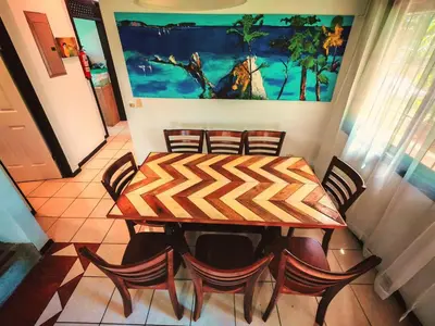 a dining room table with chairs and a painting on the wall at Valle del Arenal House Family Home in La Fortuna in Fortuna
