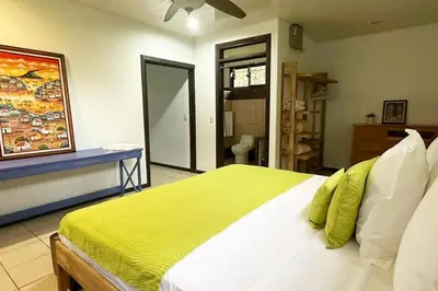 a bedroom with a large bed and a bathroom at Valle del Arenal House Family Home in La Fortuna in Fortuna
