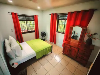 a bedroom with red curtains and a bed and a mirror at Valle del Arenal House Family Home in La Fortuna in Fortuna