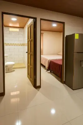 a bathroom with a bed and a refrigerator in a room at Fraijanes Mountain Stay in Alajuela City