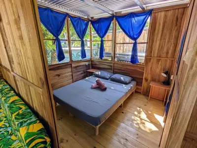 a bedroom with a bed in a room with blue curtains at Arbura in Uvita
