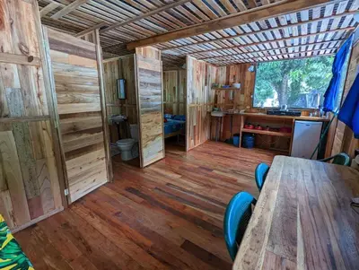 a wooden cabin with a table and a desk at Arbura in Uvita