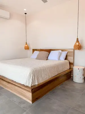 a bedroom with a wooden bed and two pendant lights at Villas Vivo in Potrero