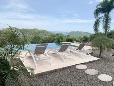 a group of three chairs sitting next to a pool at Villas Vivo in Potrero
