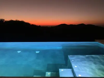 a swimming pool with a sunset in the background at Villas Vivo in Potrero