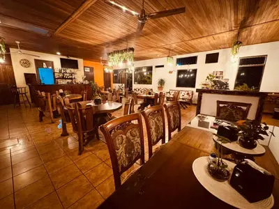 a restaurant with tables and chairs and a fireplace at Habitación doble, Hotel Aurora Inn, Nuevo Arenal in Nuevo Arenal