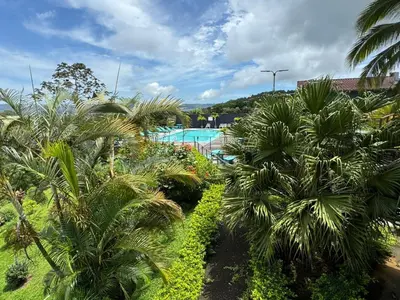 a view of a resort with palm trees and a pool at Habitación doble, Hotel Aurora Inn, Nuevo Arenal in Nuevo Arenal