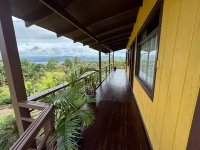 a balcony of a yellow house with a wooden floor at Habitación doble, Hotel Aurora Inn, Nuevo Arenal in Nuevo Arenal