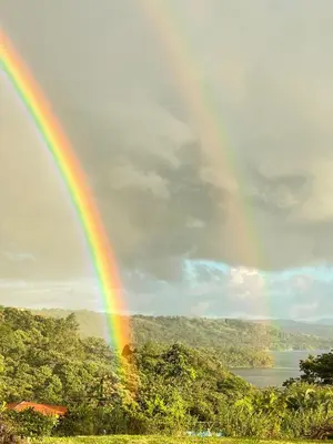 a rainbow in the sky with trees and a lake at Little Paradise in Nuevo Arenal