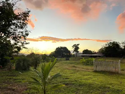a sunset in a field with a fence at Little Paradise in Nuevo Arenal