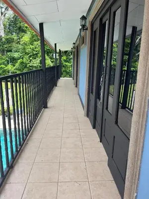a balcony with black doors and a tile floor at Casa Lapa Herradura con piscina grande privada in Herradura