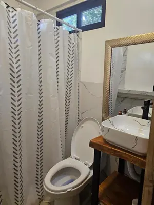 a bathroom with a toilet and a sink and a mirror at Uvita Boutique Studios in Uvita