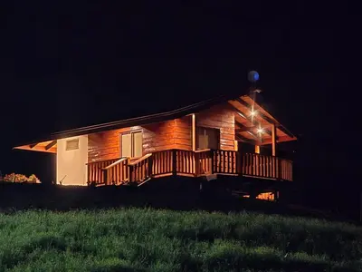 a large wooden cabin with a deck at night at San Vicente Mountain in Colón