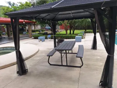 a picnic table and bench under a pavilion next to a pool at Casa Lapa Herradura Completa in Herradura