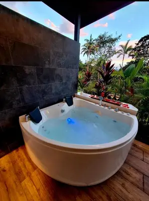 a bath tub in a room with a large window at Selvático Costa Rica in Chachagua