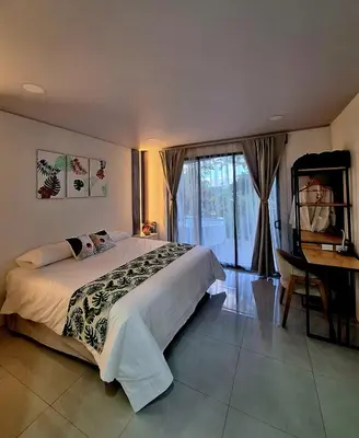 a bedroom with a bed and a desk and a window at Selvático Costa Rica in Chachagua