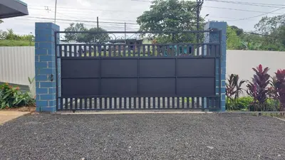 a blue gate in a driveway in front of a house at Selvático Costa Rica in Chachagua