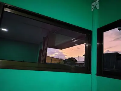a window in a green building with a sunset in the background at La Fortuna Brisas del Recuerdo in Fortuna