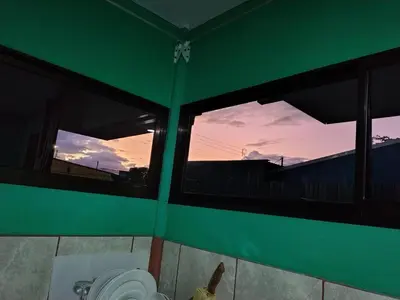 a bathroom with a green wall with windows and a urinal at La Fortuna Brisas del Recuerdo in Fortuna