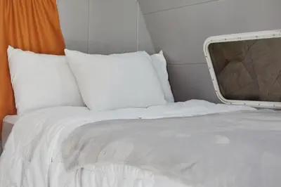 a bed with white sheets and a tv on it at Tiny Soul in Santa Teresa Beach