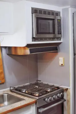 a microwave above a stove in a kitchen at Tiny Soul in Santa Teresa Beach