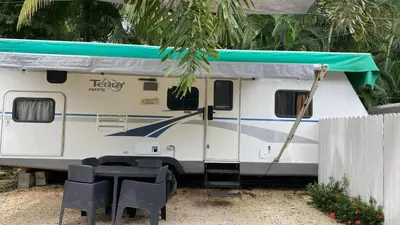a white trailer with a green roof and a table and chairs at Tiny Soul in Santa Teresa Beach