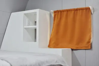 a bedroom with an orange curtain and a white cabinet at Tiny Soul in Santa Teresa Beach