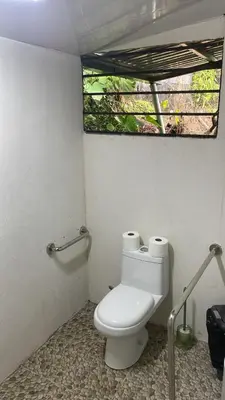 a bathroom with a white toilet with a window at Hostel La Bambú in Quepos