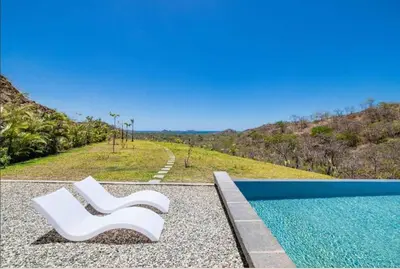 two white chairs sitting next to a swimming pool at Luxury villa Potrero in Potrero